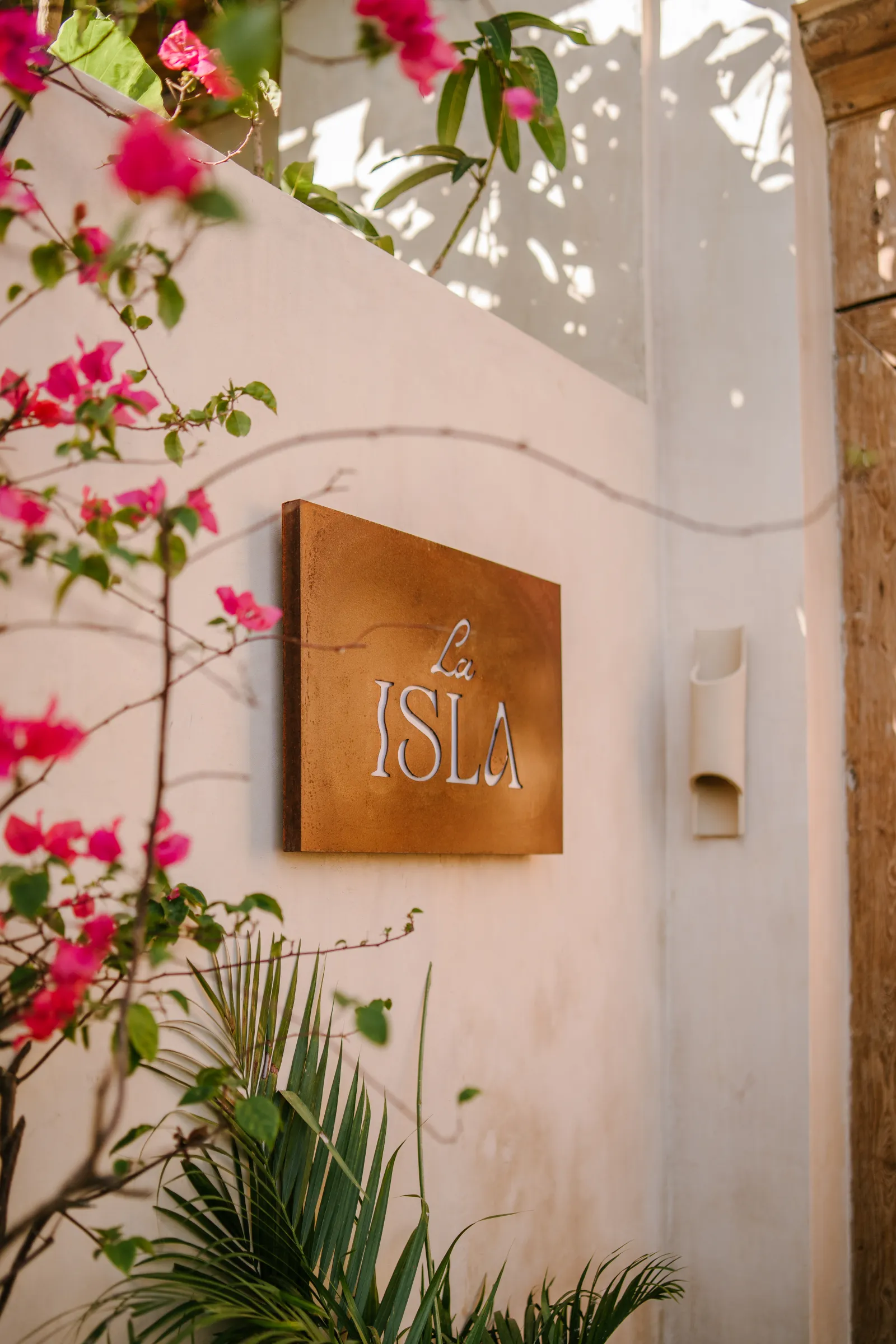 Carved wooden door framed by bougainvillea at La Isla