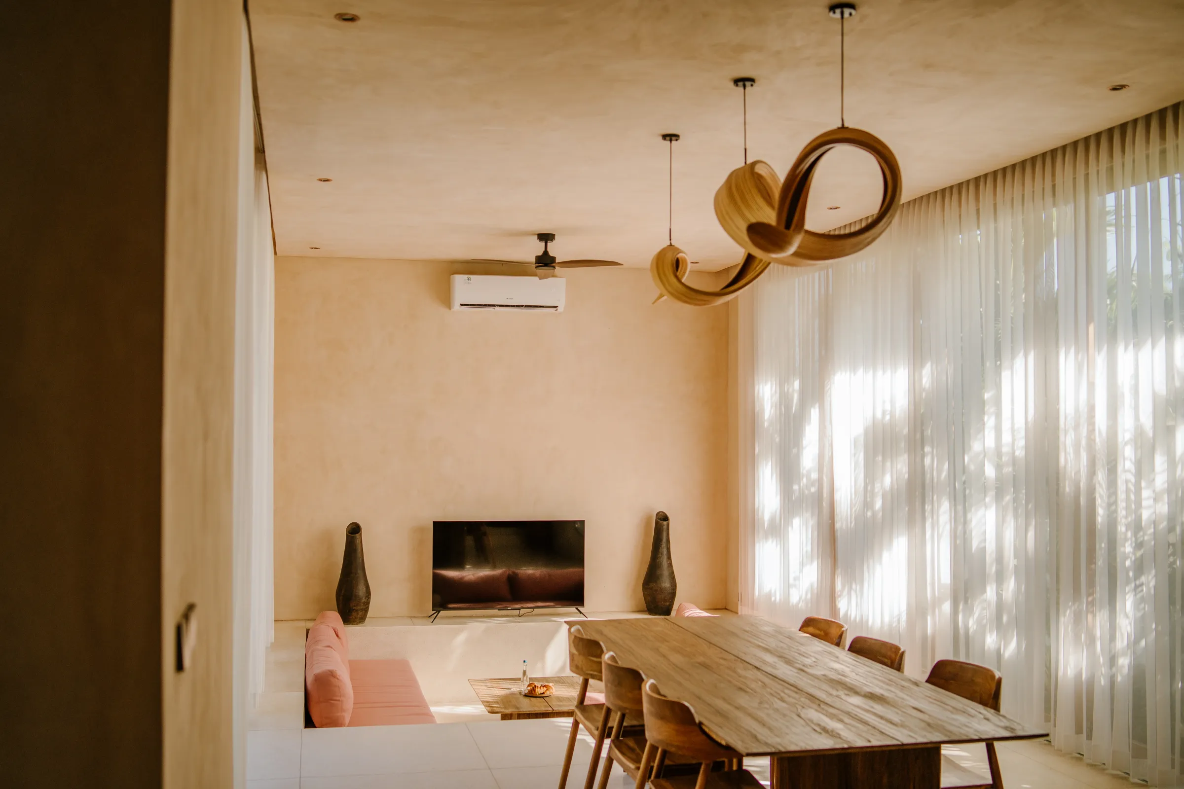 Villa dining room with long wooden table and pendant lights