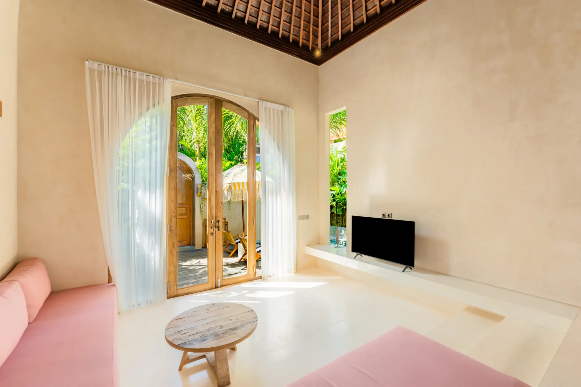 Living room with pink seating, arched doors to outdoor terrace