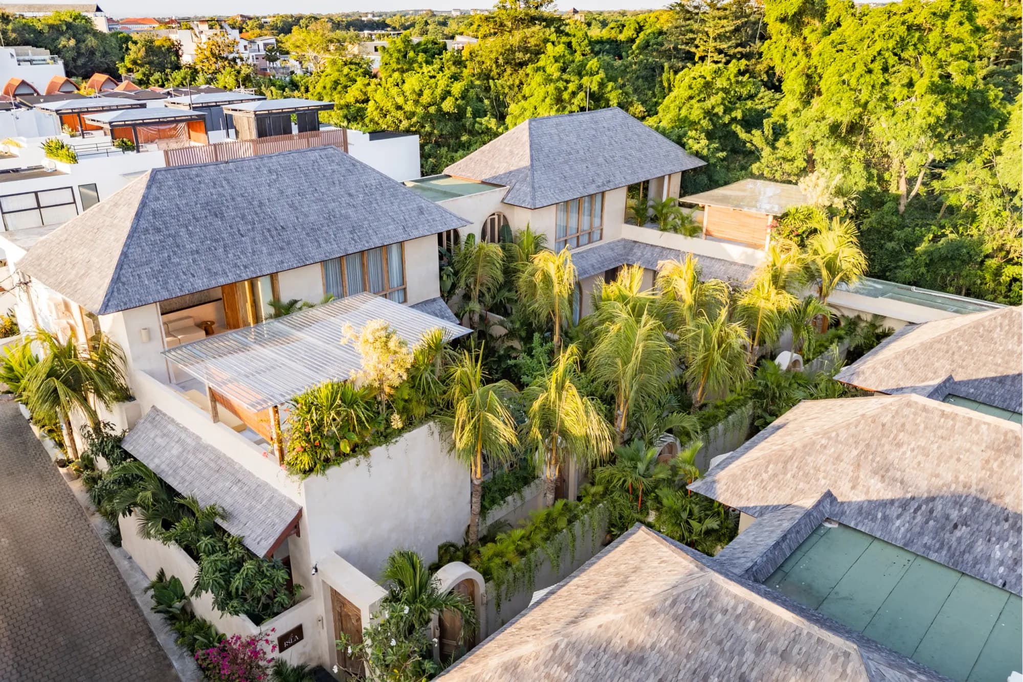Sunset aerial view of villa with thatched roofs and grounds