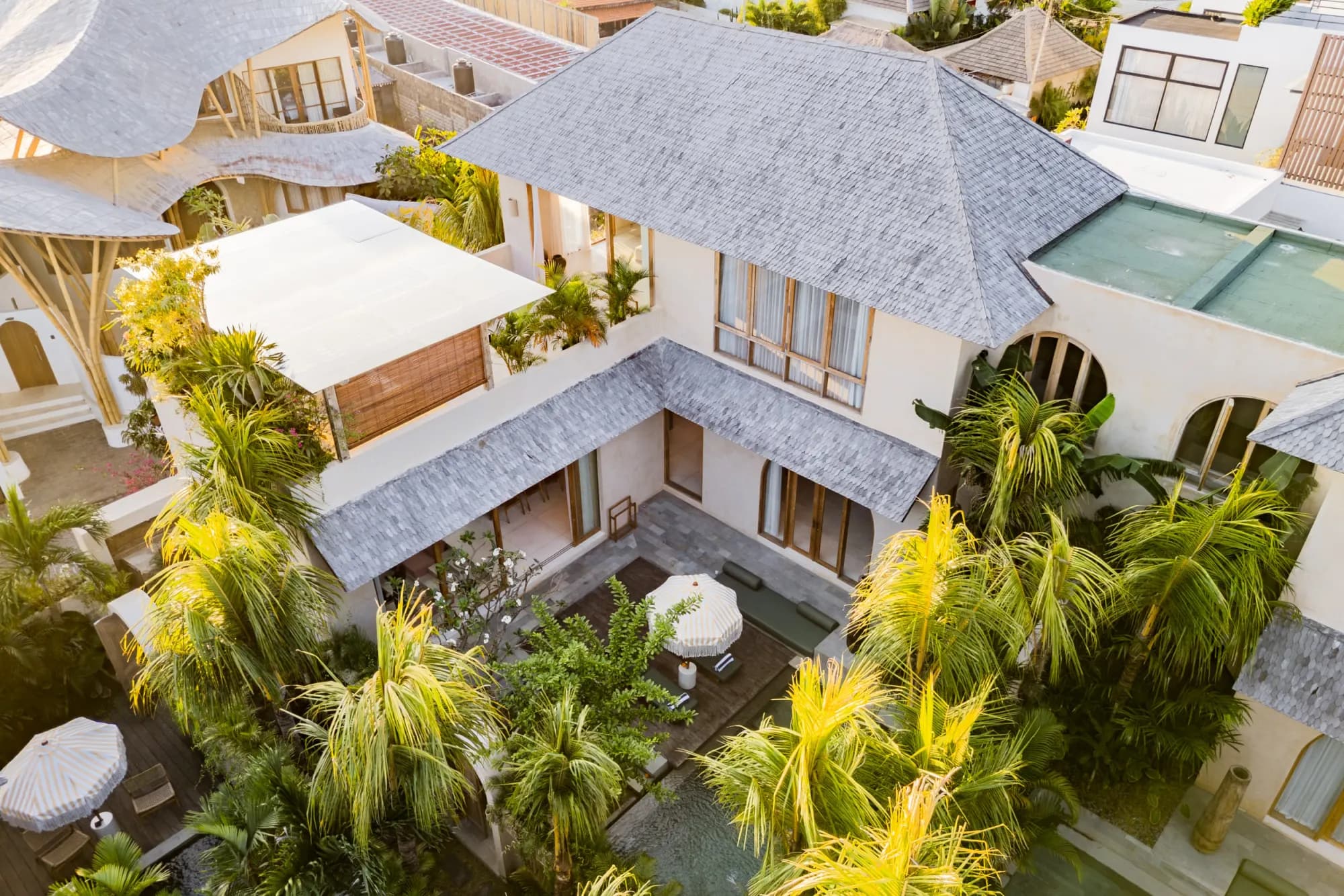 Drone view of villa complex with multiple pools and lush grounds