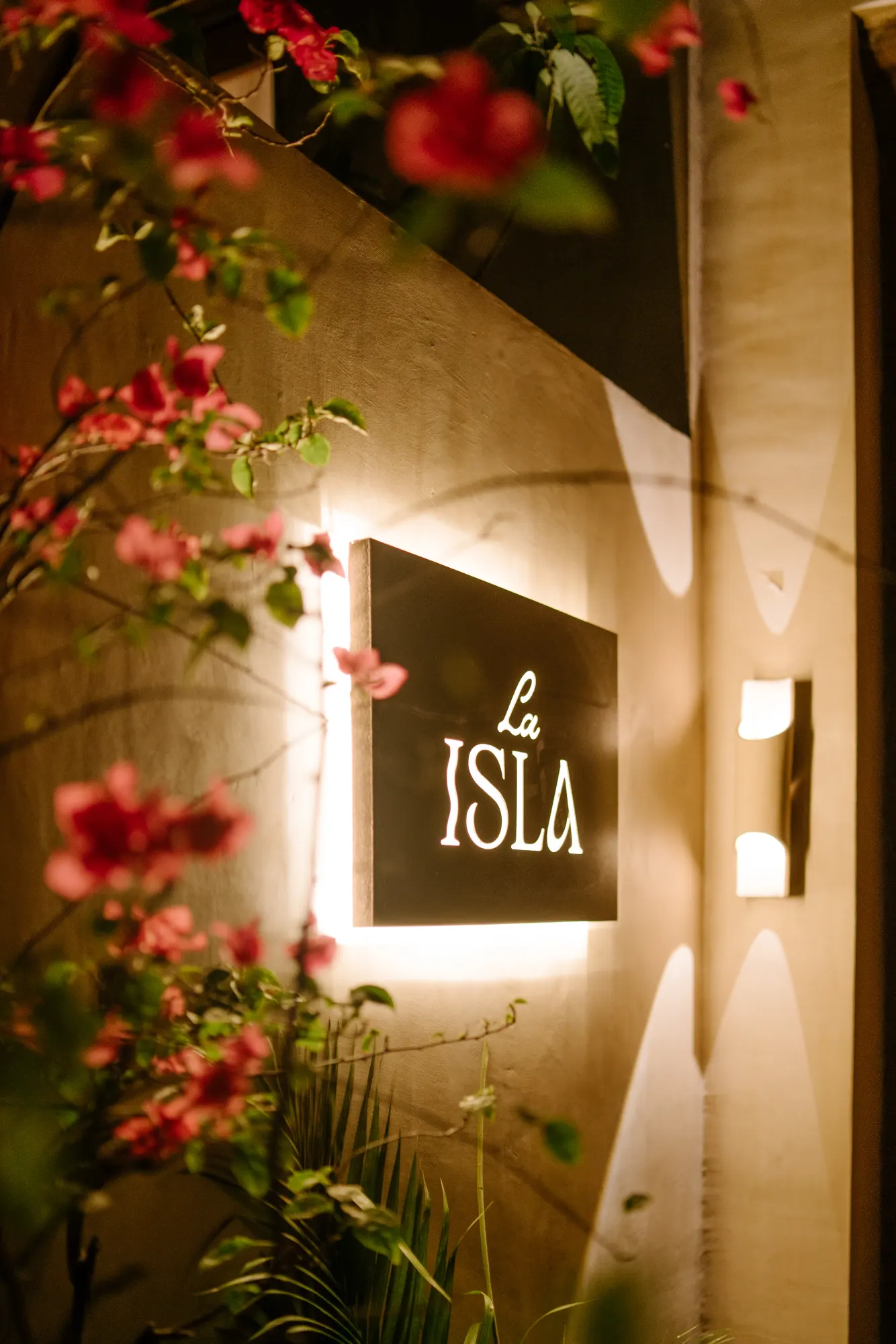 Entrance sign "La ISLA" with flowering plants