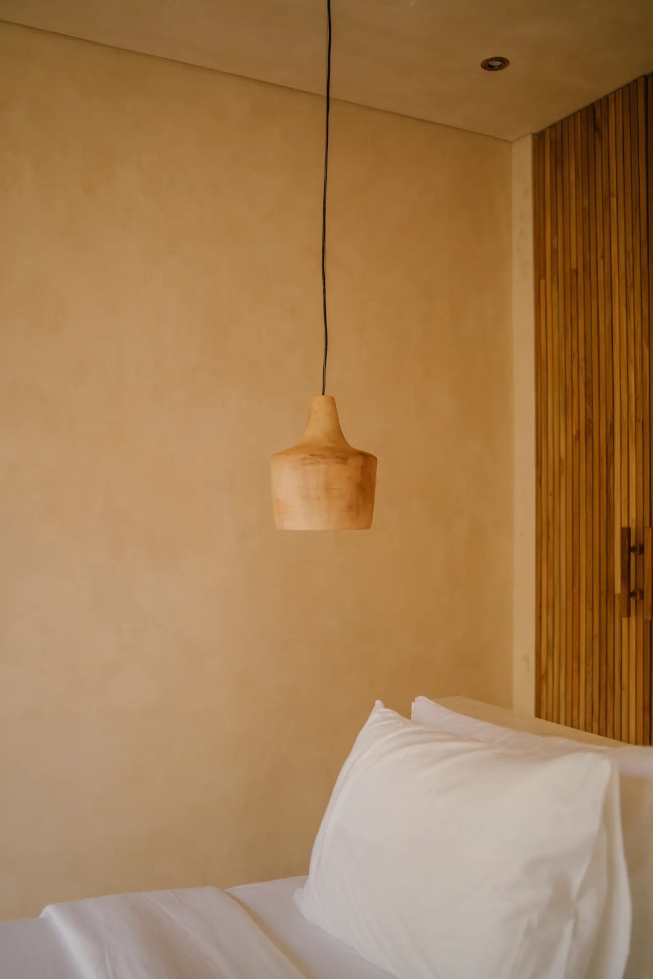 Contemporary bedroom interior with hanging wooden light fixture