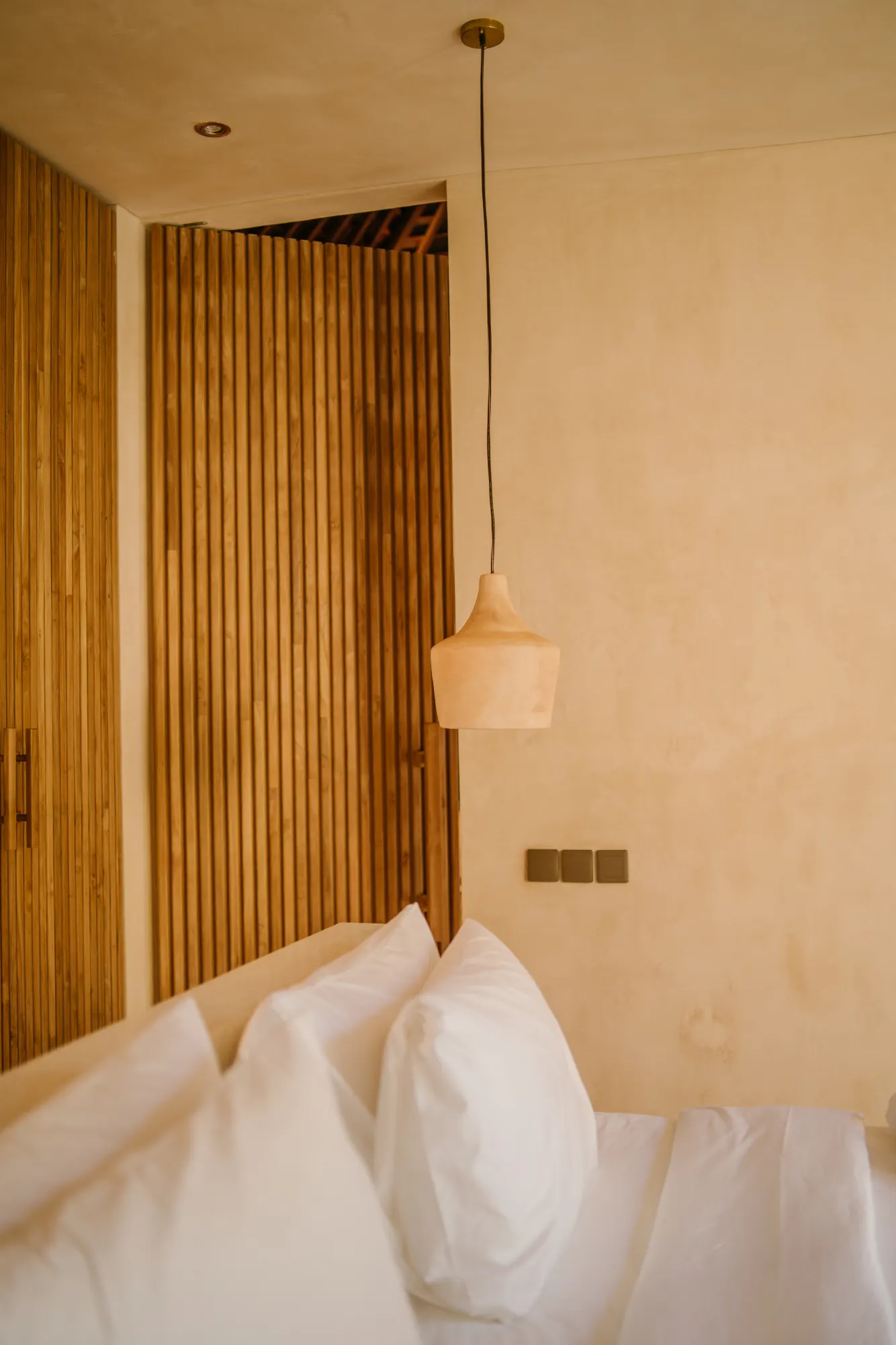 Modern bedroom with sculptural wood pendant lamp over bed