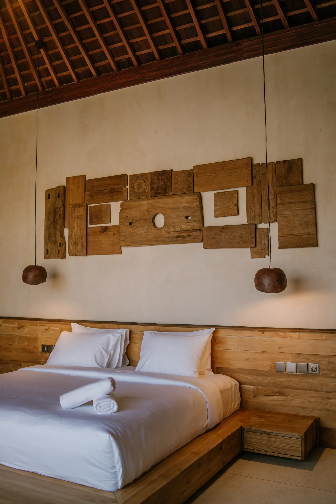 Full bedroom view showing custom wooden headpiece and bedding