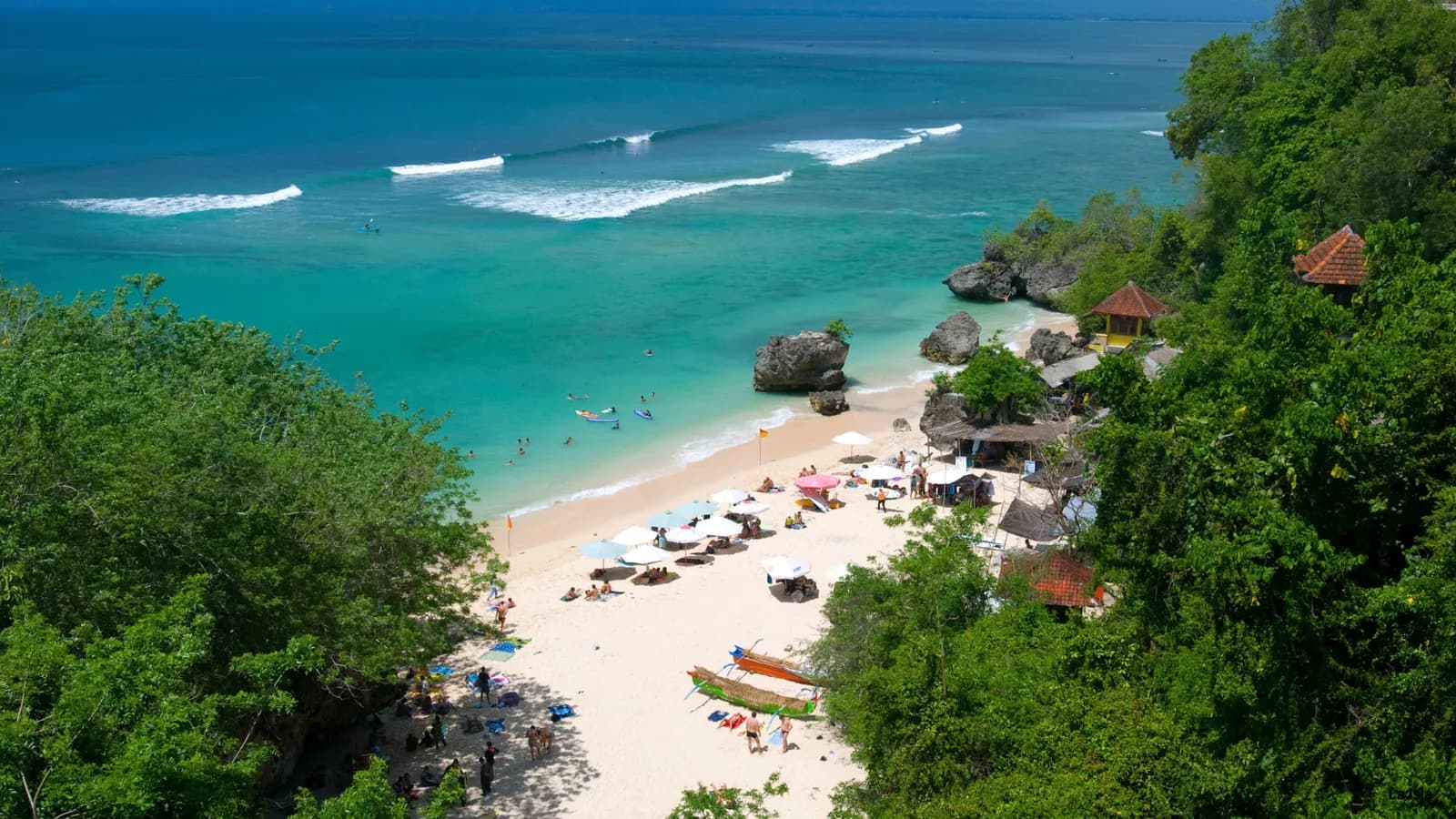 Aerial view of a turquoise Uluwatu beach with surf breaks and cliffside warungs